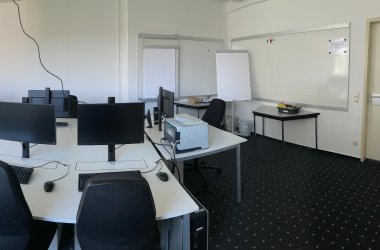 Der EDV-Raum  des IHK-Bildungszentrums Bonn/Rhein-Sieg mit Medien, Tischen, Stühlen und einem Teppichboden.