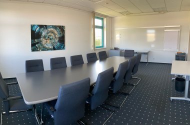 Der Konferenzraum des IHK-Bildungszentrums Bonn/Rhein-Sieg mit Medien, Tischen, Stühlen und einem Teppichboden.