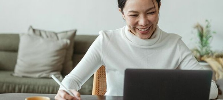 Eine Frau sitzt am Schreibtisch vor ihrem Laptop